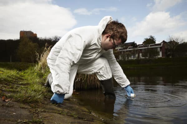 person collecting scientific water sample from lake