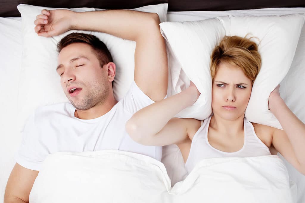 couple in bed and woman can't sleep due to her husband snoring because of sleep apnea